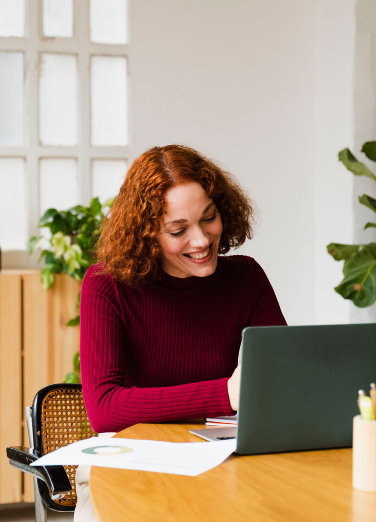 Frau mit rotem Pullover arbeitet am Laptop