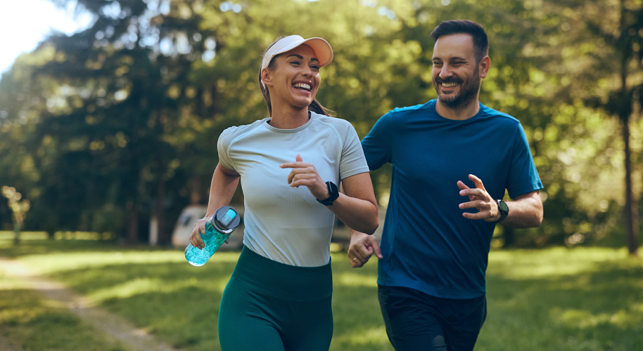 Zwei Personen joggen glücklich durch einen Park