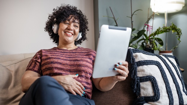 Frau an Tablet auf Couch